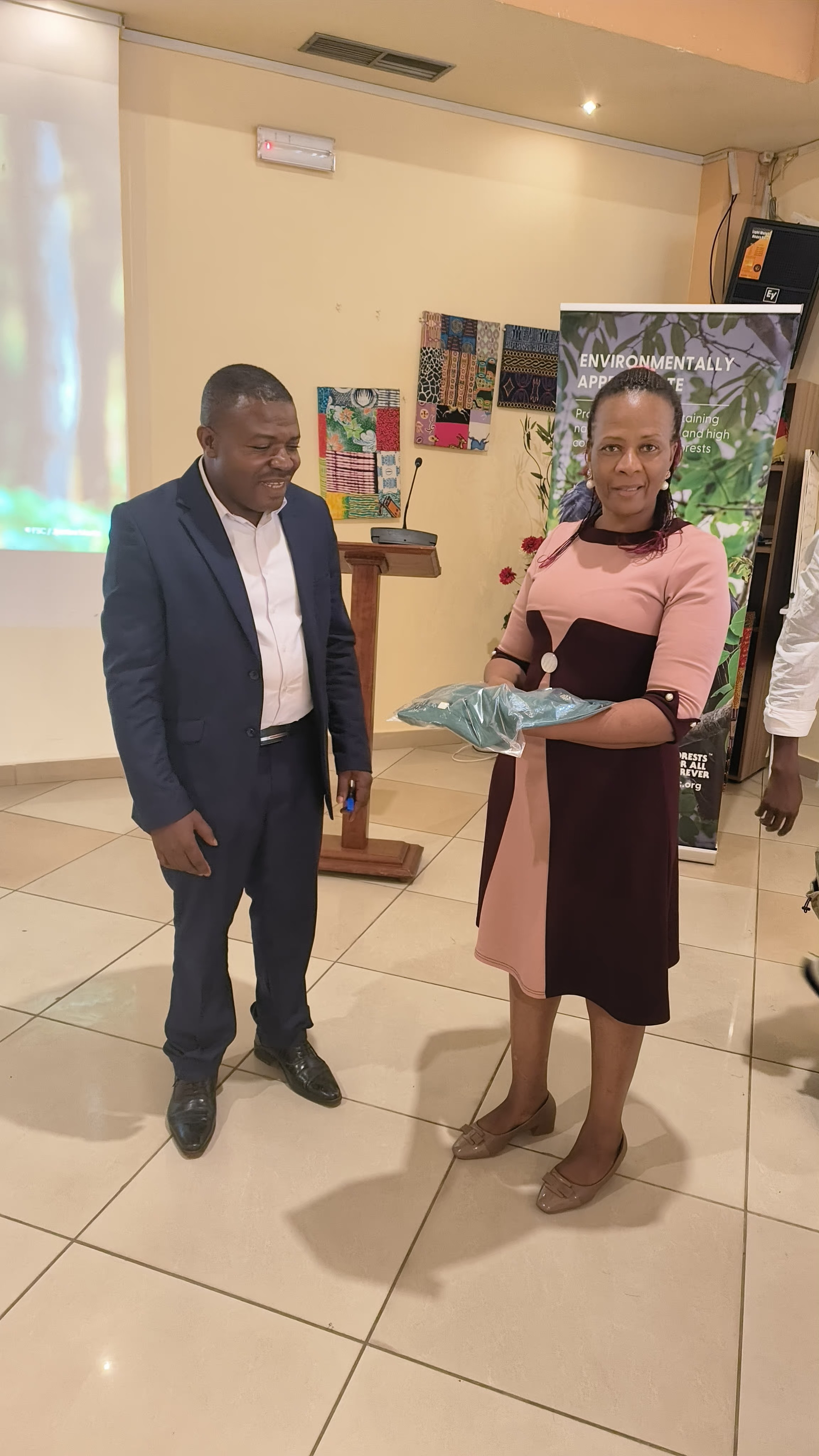 Annah Agasha, Left hands over FSC T-shirt to FSC member on the right.